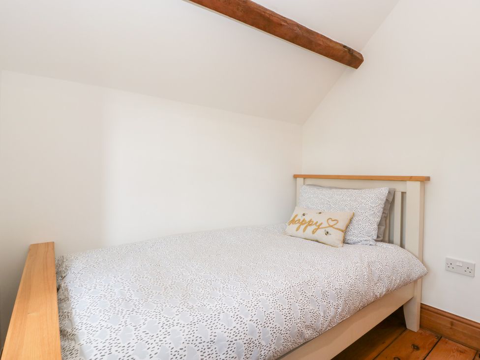 A bedroom with a single bed and pillow at Penrhiwarwydd Barn in Pontywaun