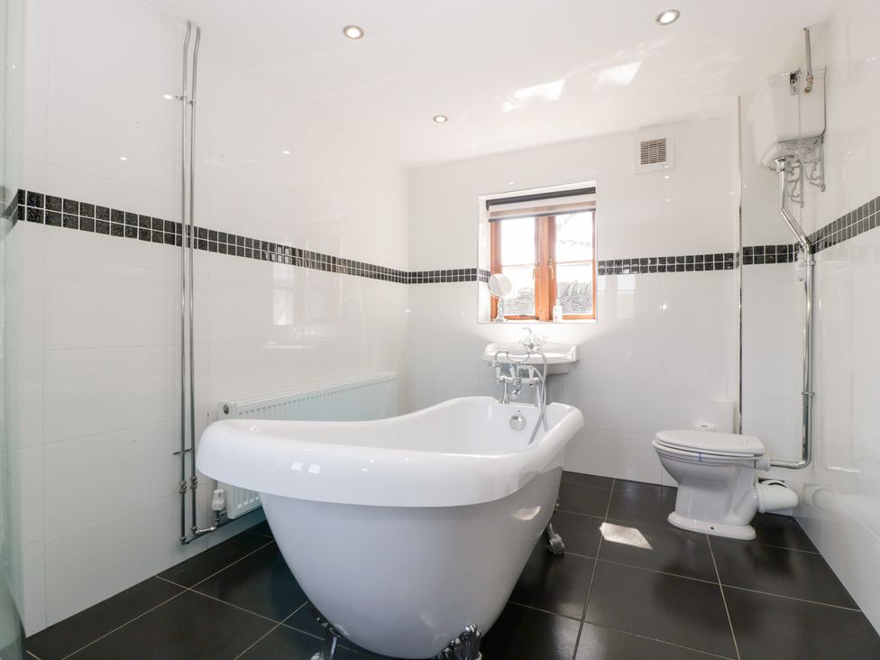 A bathroom with a bathtub, sink and toilet at Penrhiwarwydd Barn Pontywaun