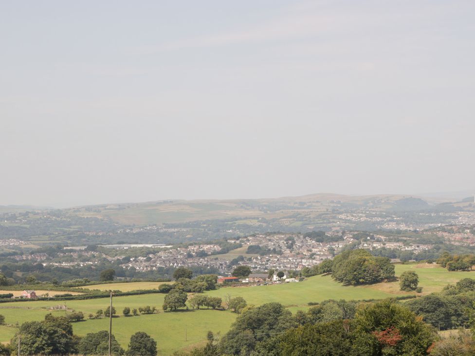 A view of fields and hills with a distant town at Penrhiwarwydd Barn Pontywaun