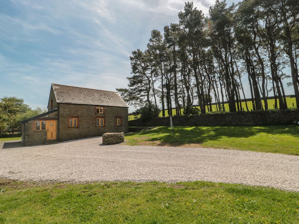 A house with a gravel driveway and trees at Penrhiwarwydd Barn Pontywaun