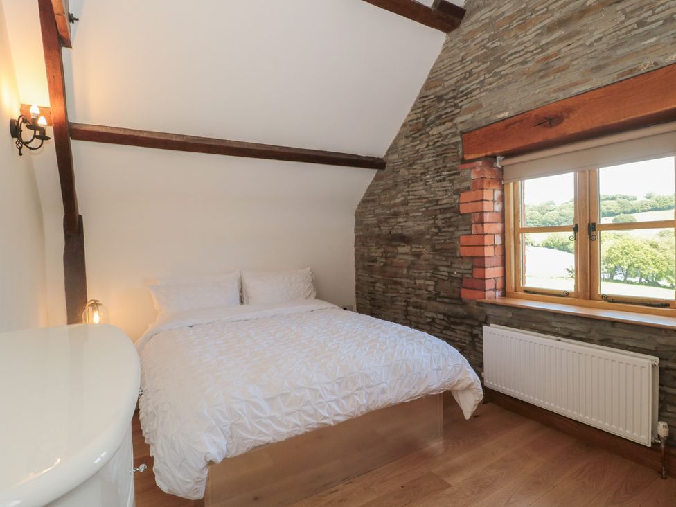A bedroom with a bed and window at Penrhiwarwydd Barn Pontywaun