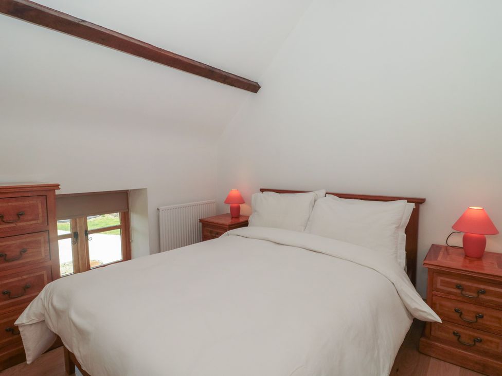 A bedroom with a bed and nightstands at Penrhiwarwydd Barn in Pontywaun