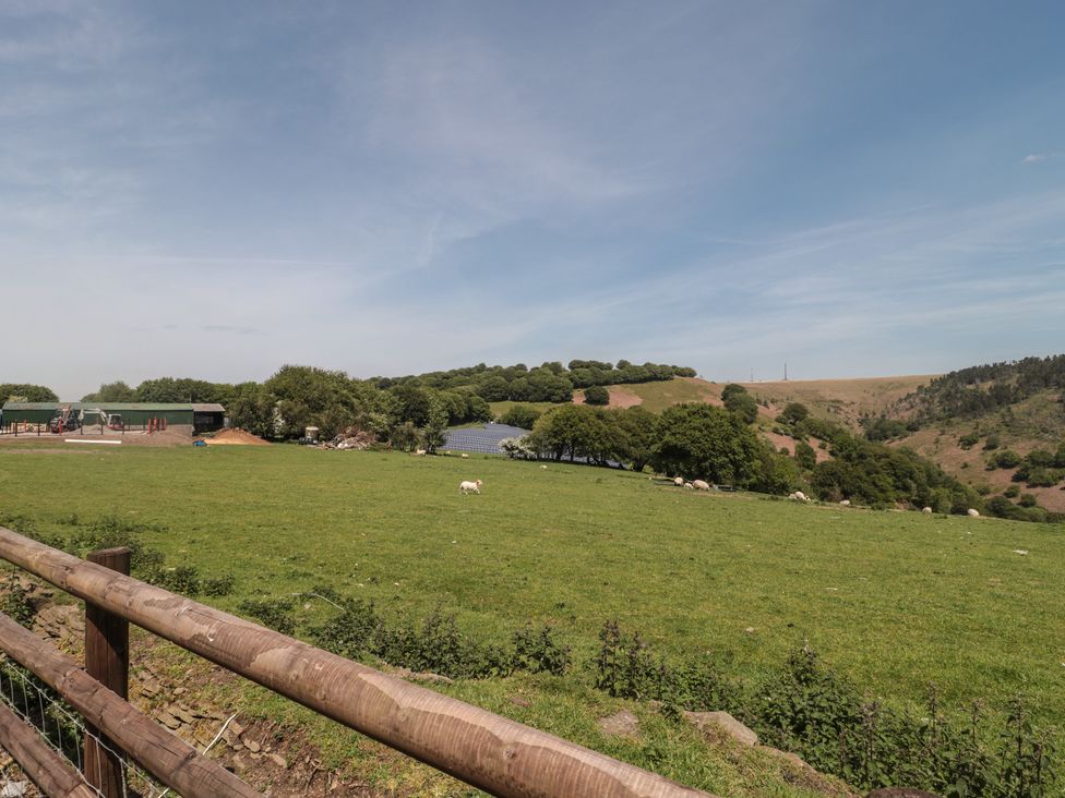 A field with sheep and a building in the background at Penrhiwarwydd Barn in Pontywaun