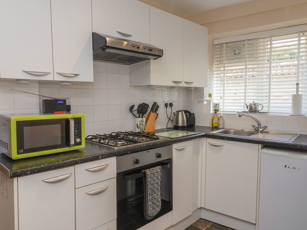 A kitchen with white cabinets and appliances at Enginefield in Combe Martin