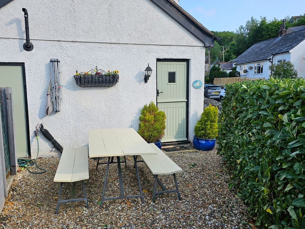 An outdoor area with a table and benches at Dove Cottage in Llanfair Talhaiarn