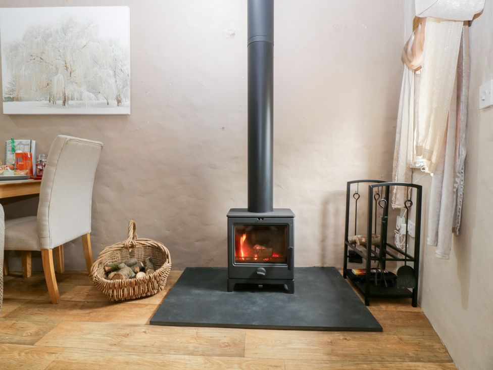 A living room with a stove and table at Caner Bach Lodge Blackmill
