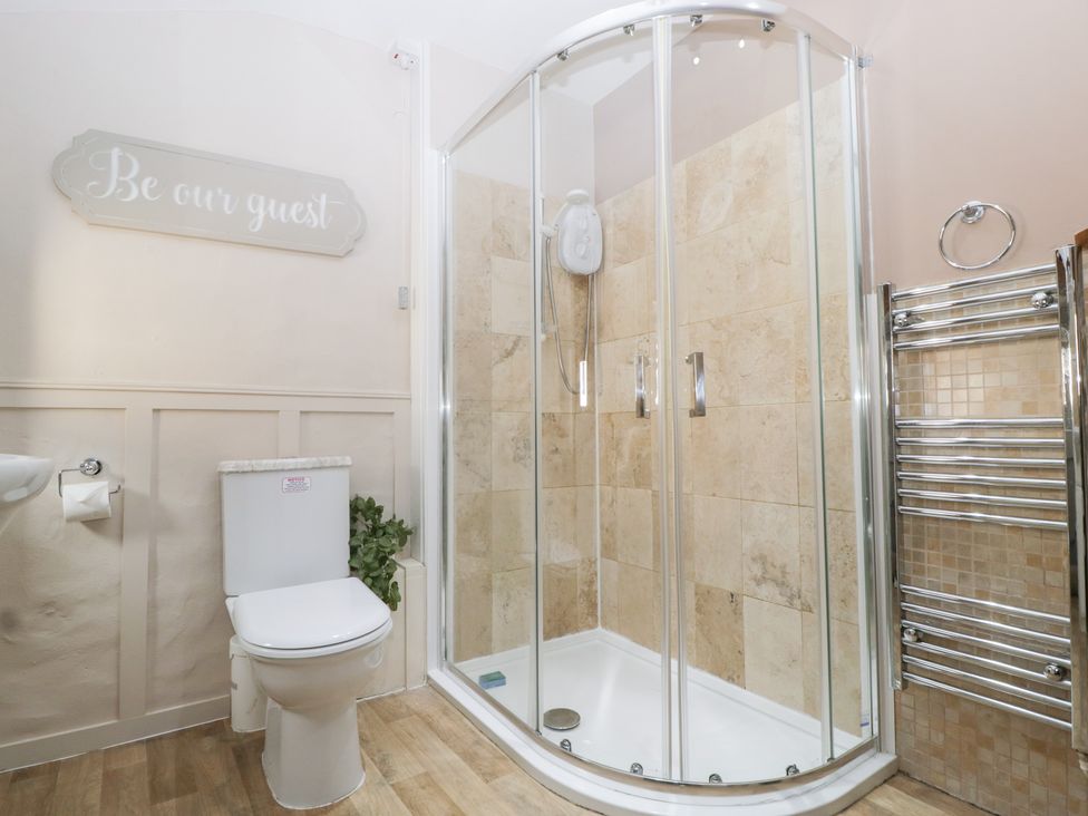 A bathroom with a shower, toilet and towel radiator at Caner Bach Lodge in Blackmill