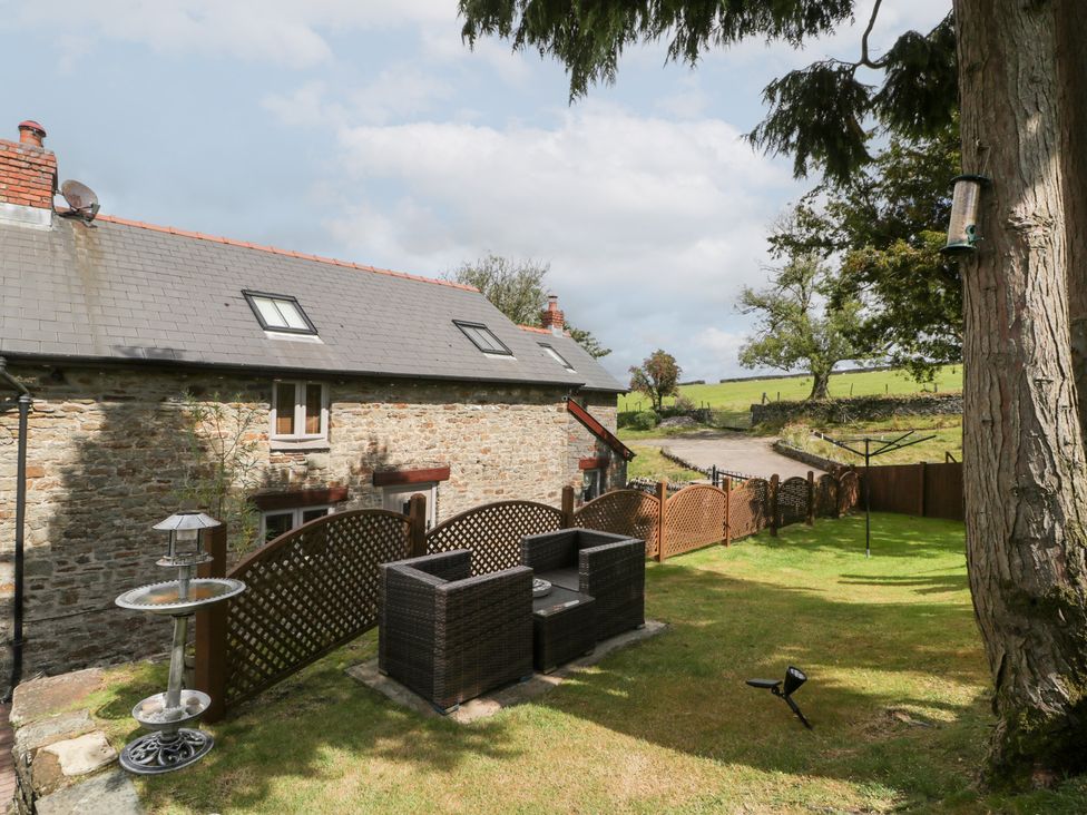 A garden with a house and seating area at Caner Bach Lodge in Blackmill