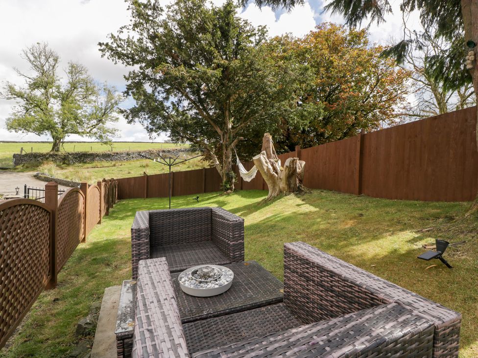 A garden with outdoor seating and a hammock at Caner Bach Lodge in Blackmill
