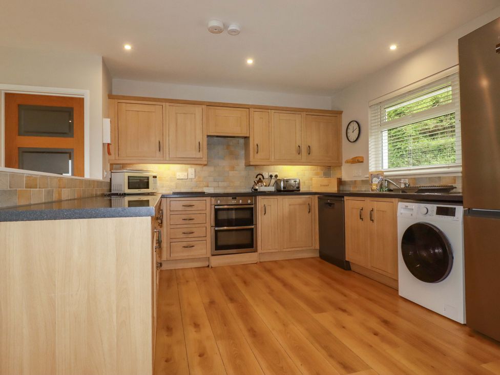 A kitchen with wooden cabinets and appliances at The Meadow in Feock near Carnon Downs