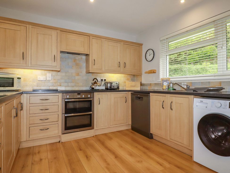 A kitchen with wooden cabinets and appliances at The Meadow in Feock near Carnon Downs