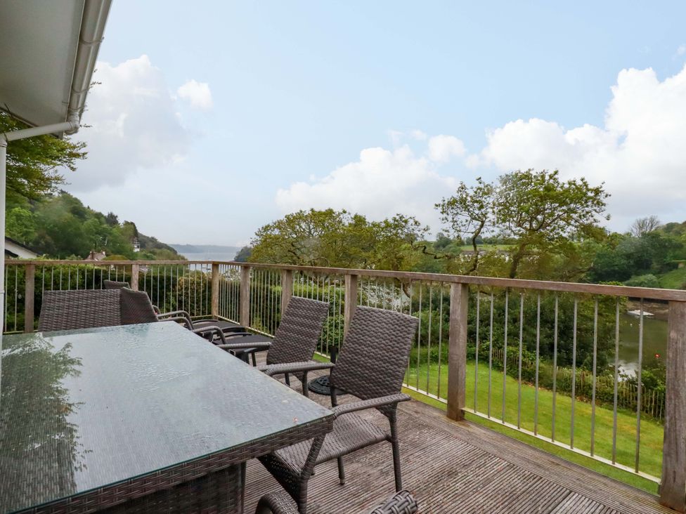 A patio area with a table and chairs overlooking water at The Meadow in Feock near Carnon Downs