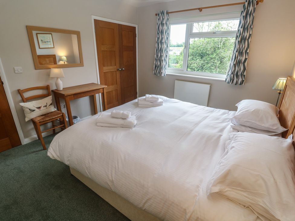 A bedroom with a bed, table, and lamp at The Meadow in Feock near Carnon Downs