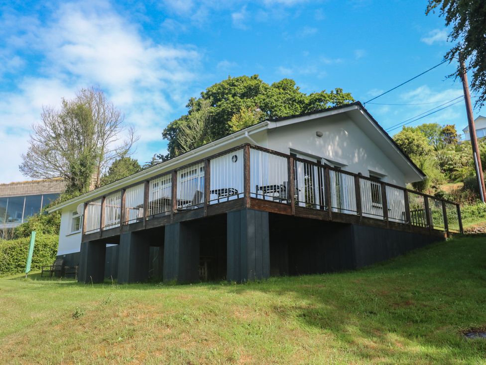 A house with a deck surrounded by grass and trees at The Meadow in Feock near Carnon Downs
