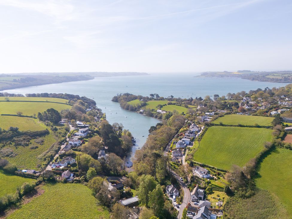 An aerial view of a river with houses and fields at The Meadow in Feock near Carnon Downs