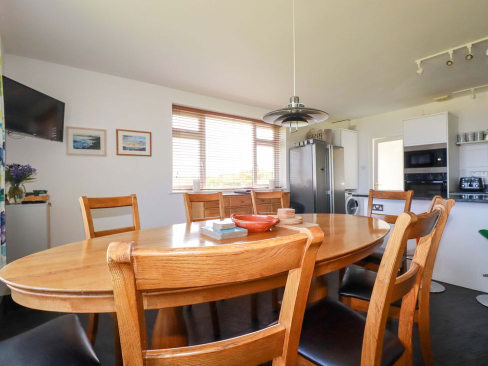 A dining room with a wooden table and chairs at Pentreath in Crantock