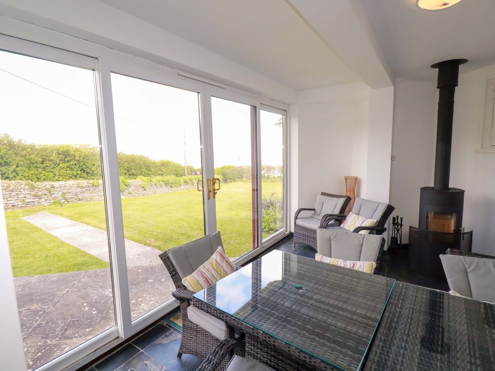 A conservatory with glass doors and seating at Pentreath in Crantock