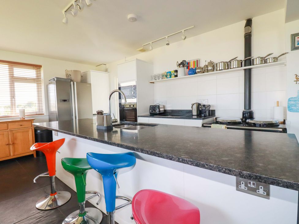 A kitchen with bar stools and cooking appliances at Pentreath in Crantock