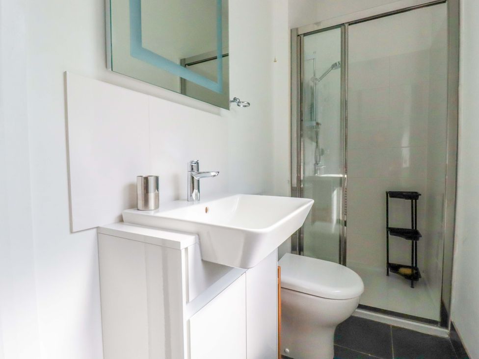 A bathroom with sink, toilet, shower and storage shelf at Pentreath in Crantock