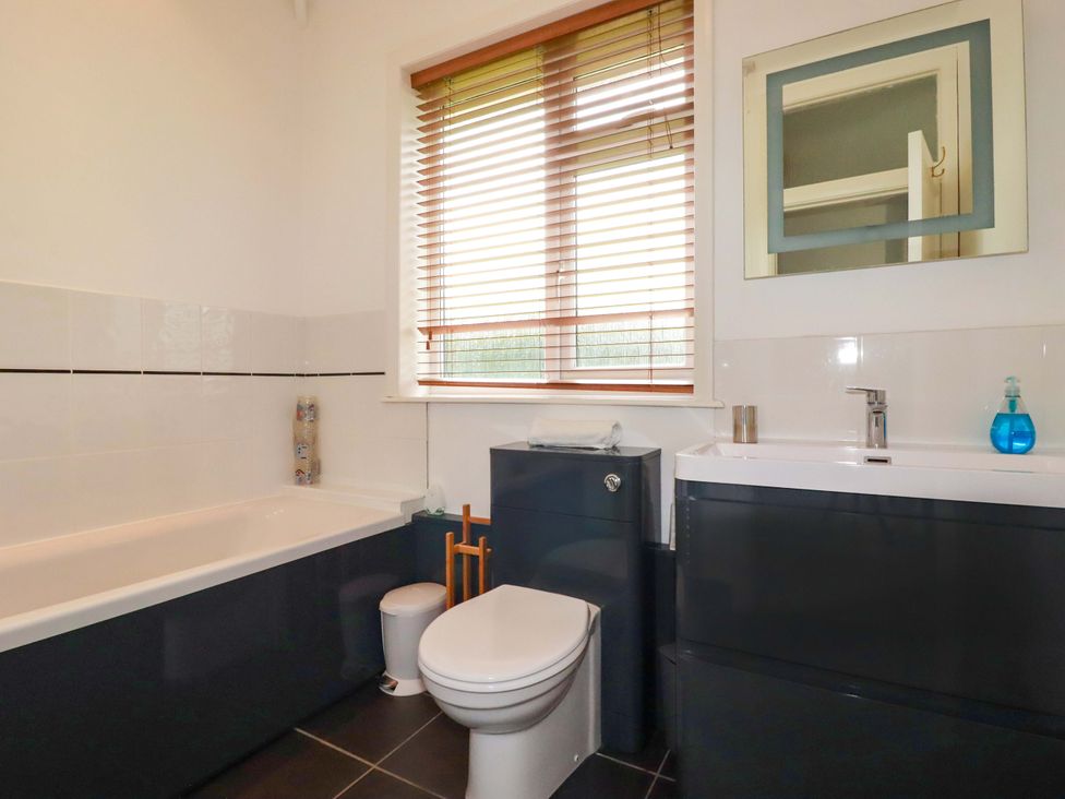 A bathroom with a bathtub, toilet, and sink at Pentreath in Crantock