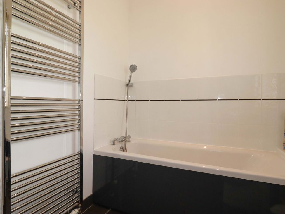 A bathroom with a bathtub and towel radiator at Pentreath Crantock