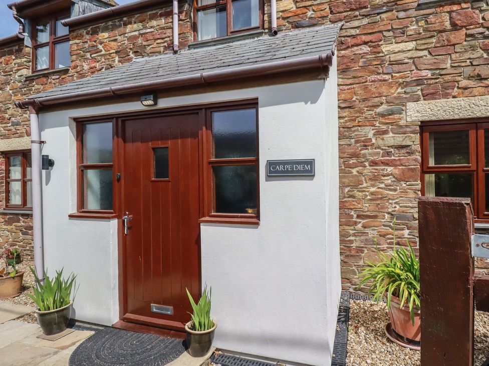 An entrance with a wooden door and stone wall at Carpe Diem in Crantock