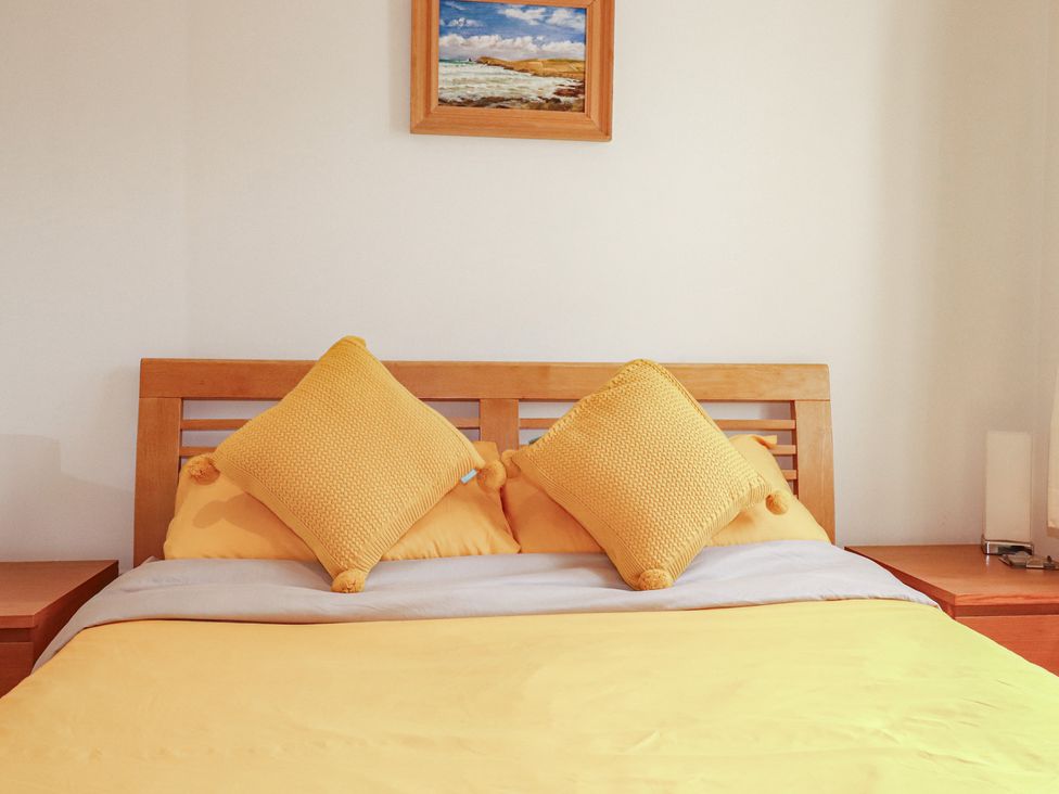 A bed with yellow bedspread and pillows in a bedroom at Carpe Diem in Crantock