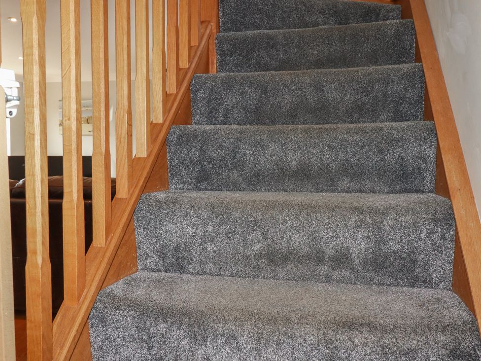 A staircase with carpet and wooden railing at Carpe Diem in Crantock