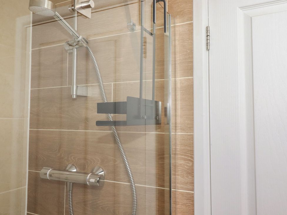 A shower with a chrome showerhead and handle in a bathroom at Carpe Diem Crantock