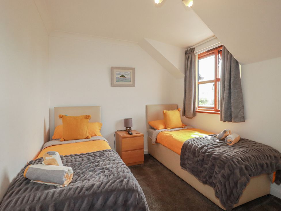 A bedroom with two beds and a nightstand at Carpe Diem in Crantock
