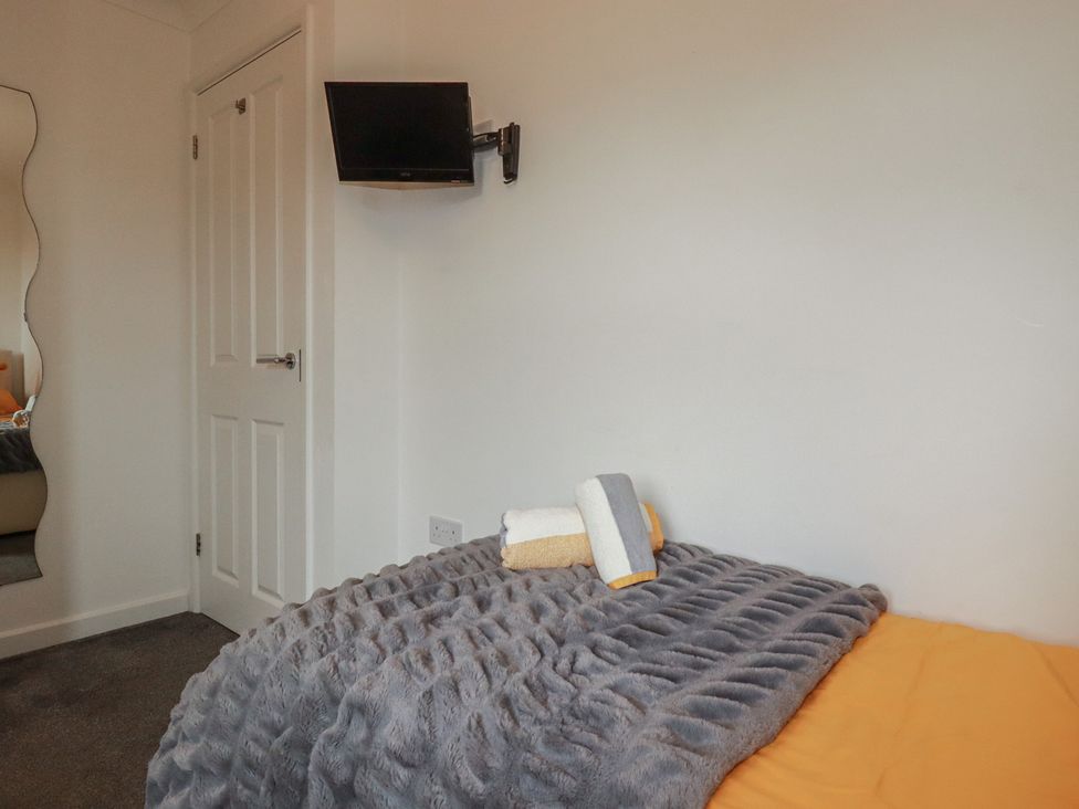 A bedroom with a bed and a television mounted on the wall at Carpe Diem in Crantock