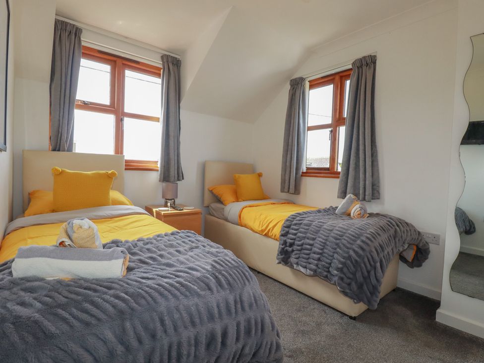 A bedroom with two beds and a nightstand at Carpe Diem in Crantock