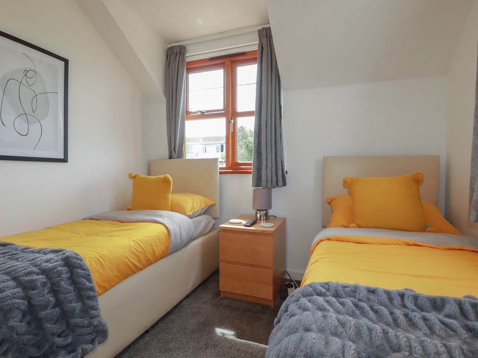 A bedroom with two beds and a nightstand at Carpe Diem in Crantock