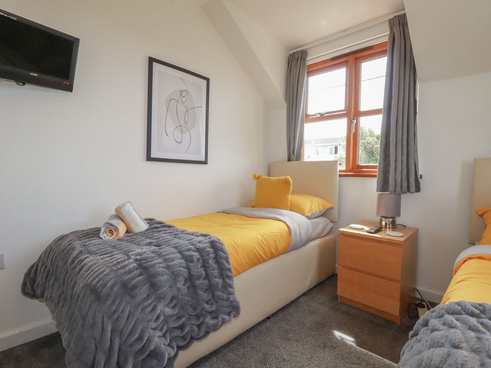 A bedroom with two beds and a nightstand at Carpe Diem in Crantock