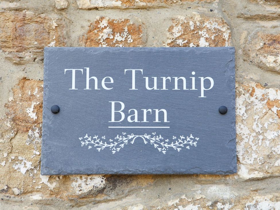 A sign displaying The Turnip Barn on a stone wall