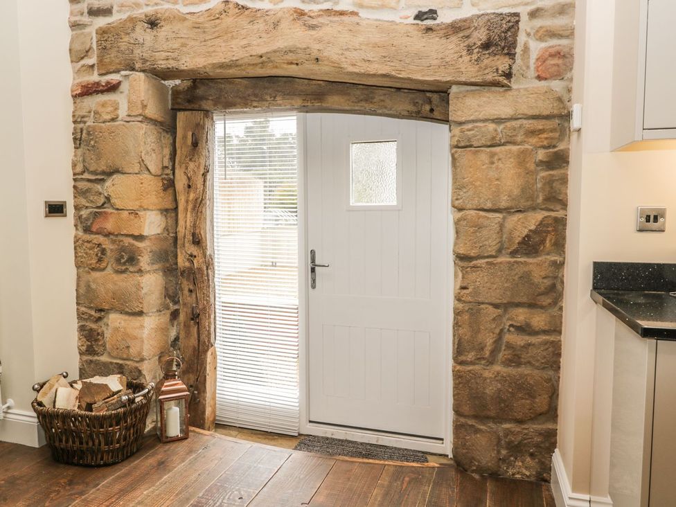 An entrance area with a stone wall and white door at The Turnip Barn in 