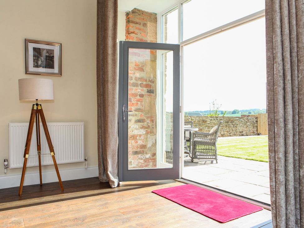 A living room with a door leading to outdoor seating at The Turnip Barn 