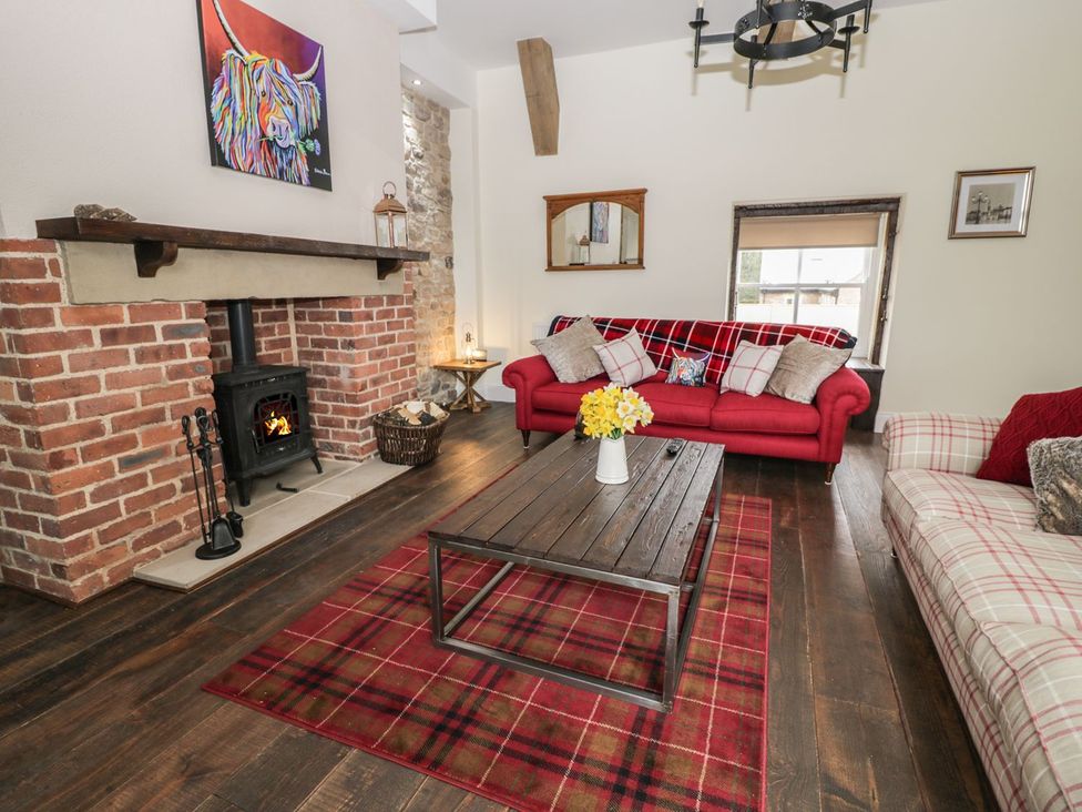 A living room with a red sofa and fireplace at The Turnip Barn in 