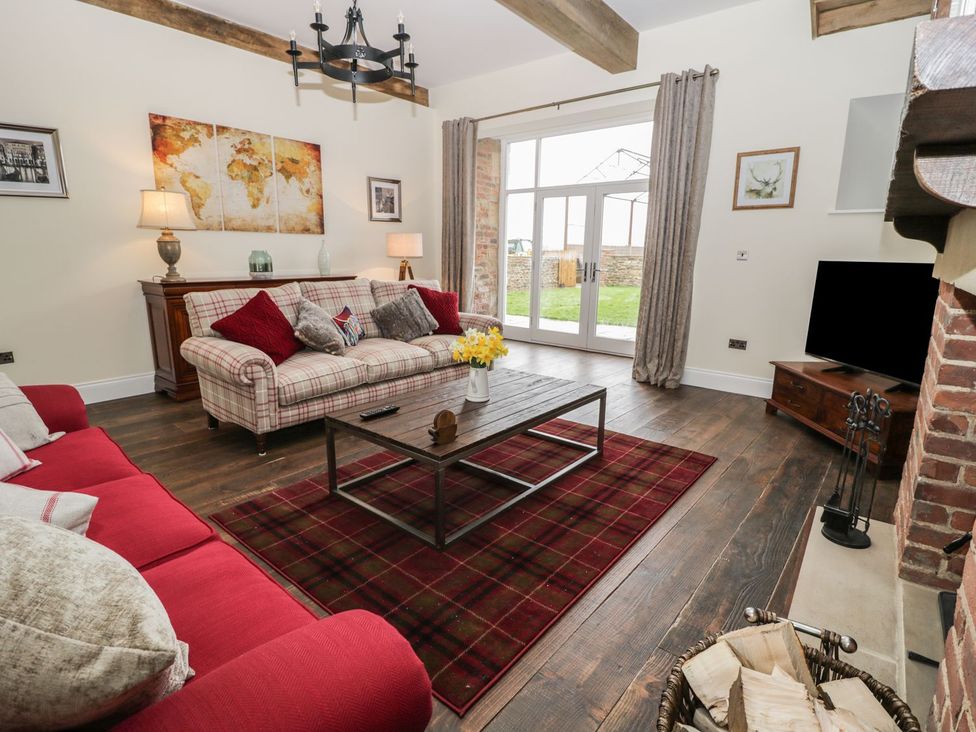 A living room with a sofa, coffee table, and television at The Turnip Barn in 