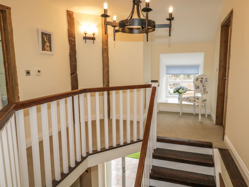 A hallway with a staircase and a chair at The Turnip Barn in 