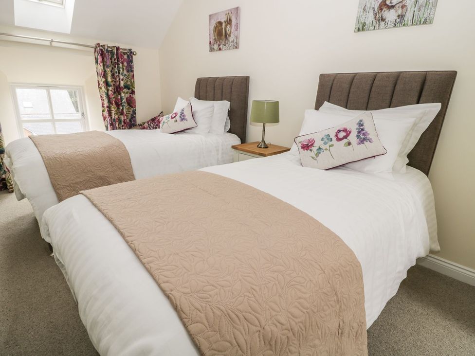 A bedroom with two single beds and a bedside table at The Turnip Barn