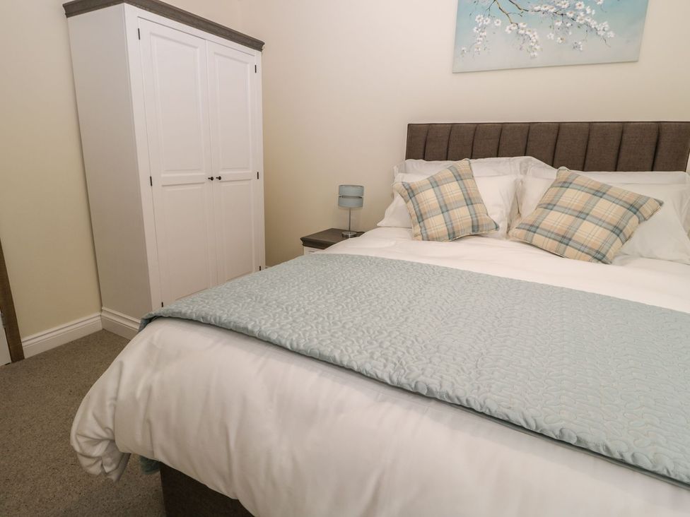A bedroom with a bed, wardrobe, and lamp at The Turnip Barn
