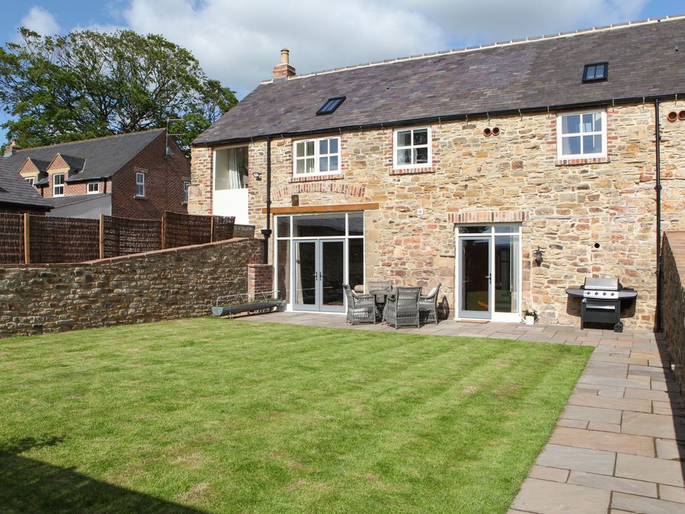 A garden with stone wall and patio furniture at The Turnip Barn in 