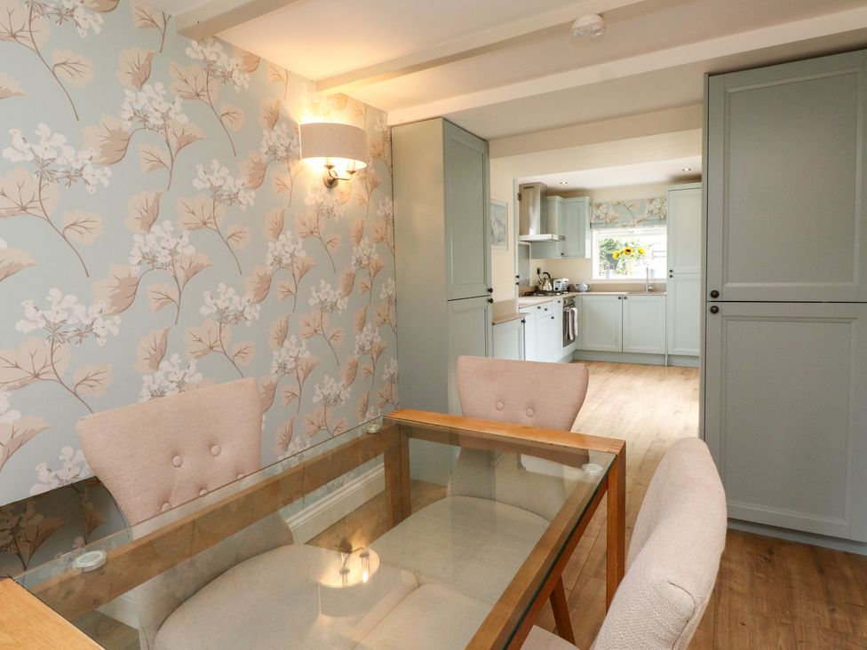 A dining room with a table and chairs leading to a kitchen at Tan Y Goeden in Morfa Nefyn