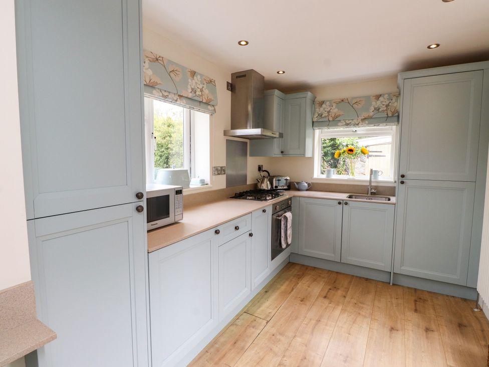 A kitchen with cabinets, stove, microwave and sink at Tan Y Goeden in Morfa Nefyn