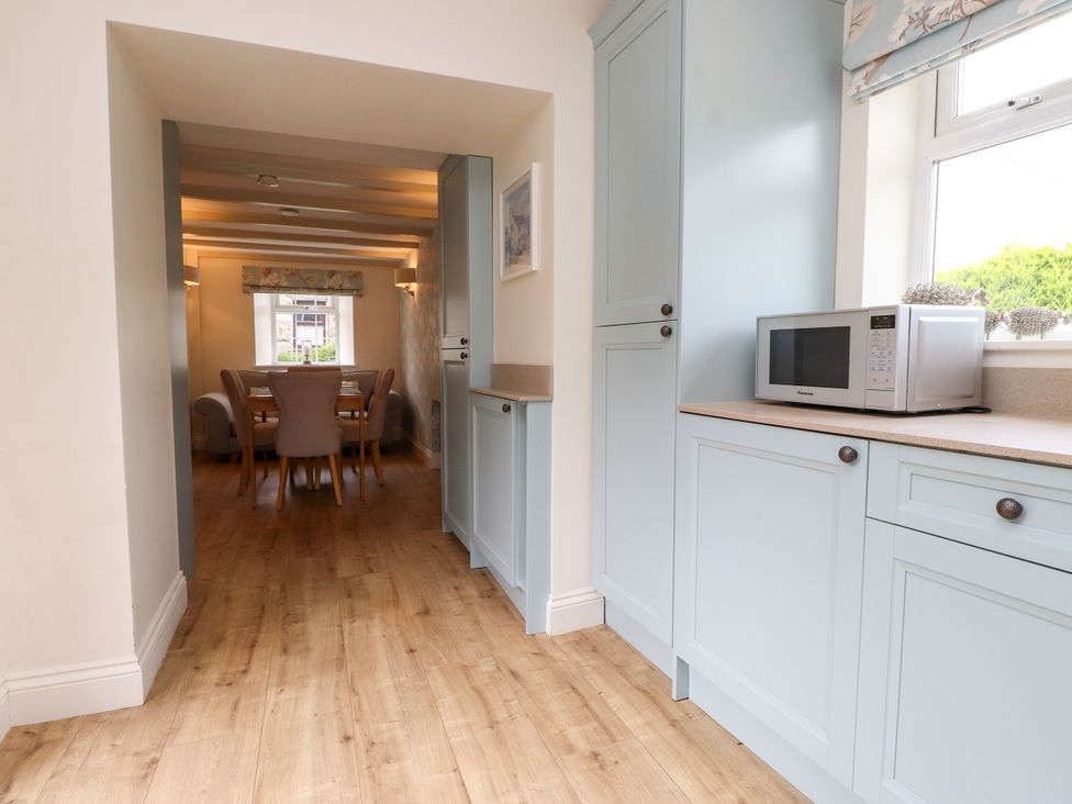 A kitchen with a microwave and table with chairs at Tan Y Goeden in Morfa Nefyn