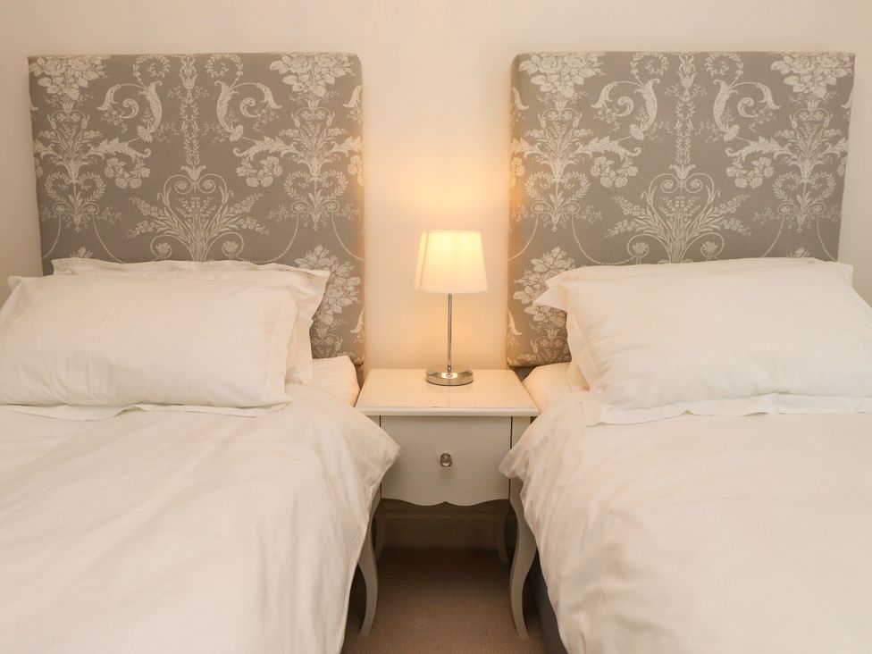 A bedroom with two beds and a lamp at Tan Y Goeden in Morfa Nefyn