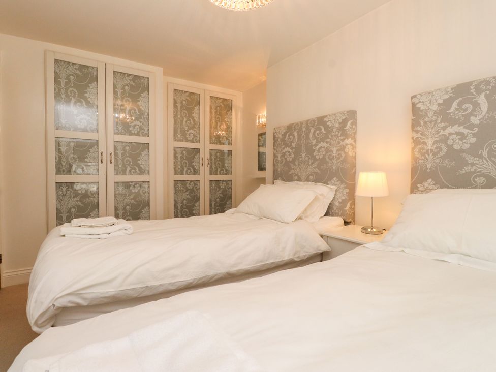 A bedroom with two beds and a wardrobe at Tan Y Goeden in Morfa Nefyn