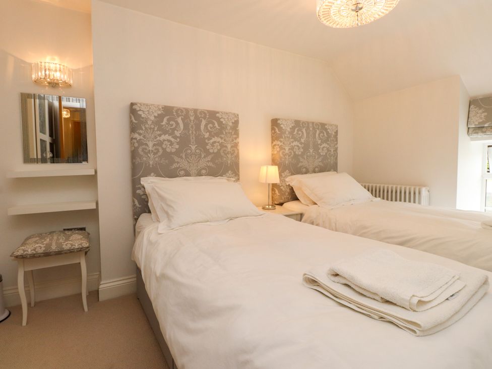 A bedroom with twin beds and a mirror at Tan Y Goeden in Morfa Nefyn