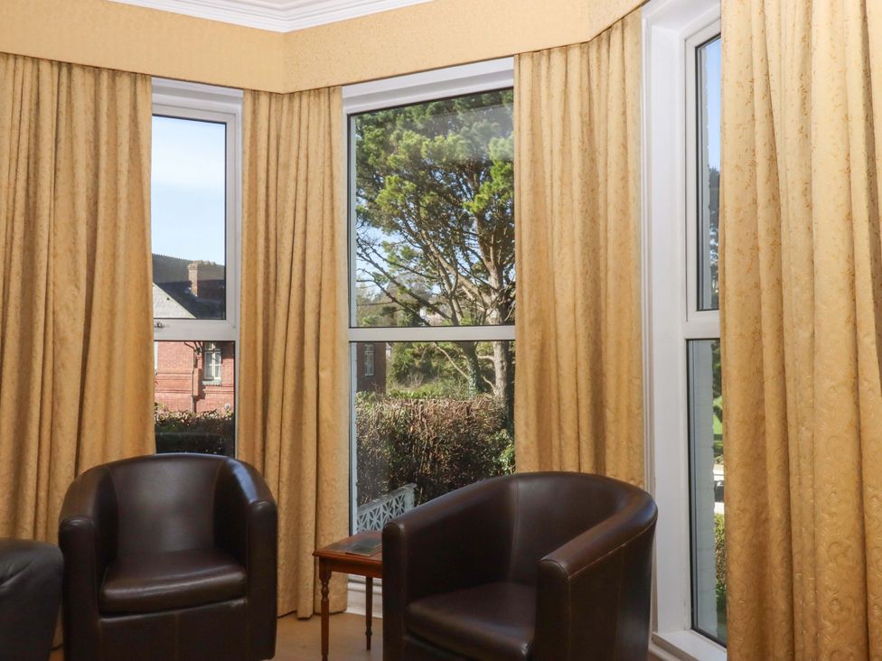 A sitting room with two chairs and windows at Avenue Park Villa in Torquay